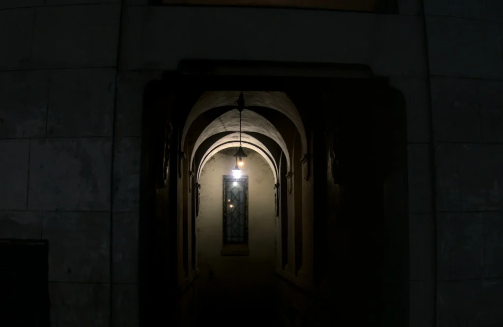 Corredor escuro em arco com luz ao fundo